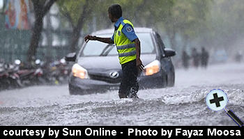 courtesy The Edition - A police officer guides traffic amid pouring rain in Male City - (Sun Photo- Fayaz Moosa)